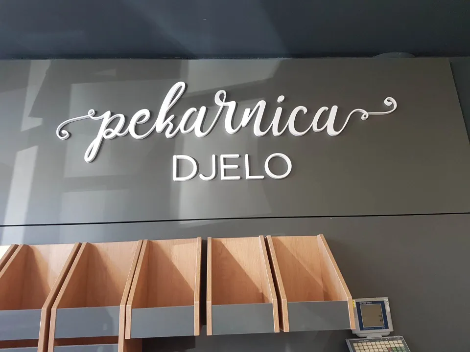Script-logo lettering on a bakery wall above wooden shelves