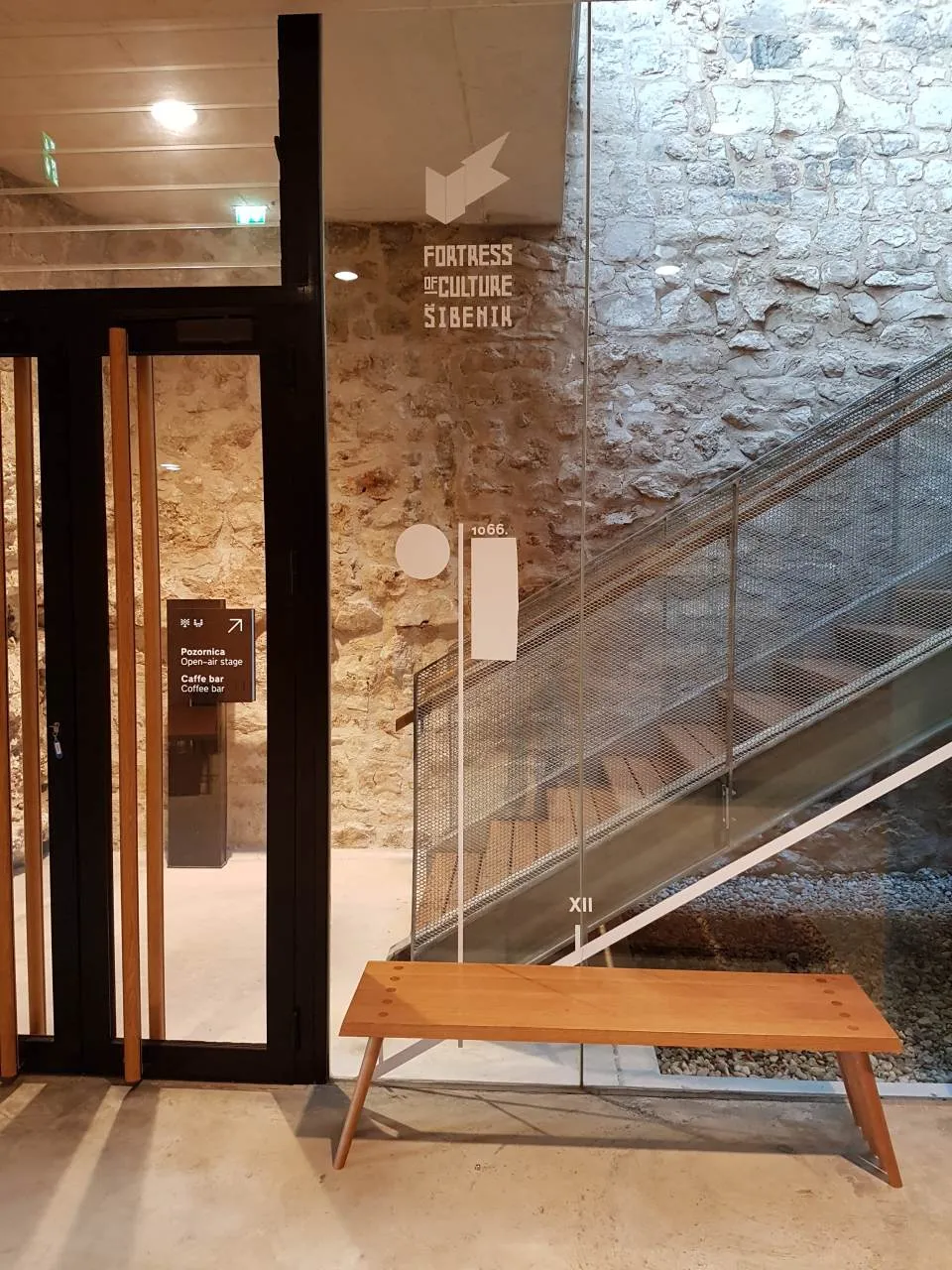 Natpis Tvrđave kulture Šibenik na kamenom zidu uz staklene stube